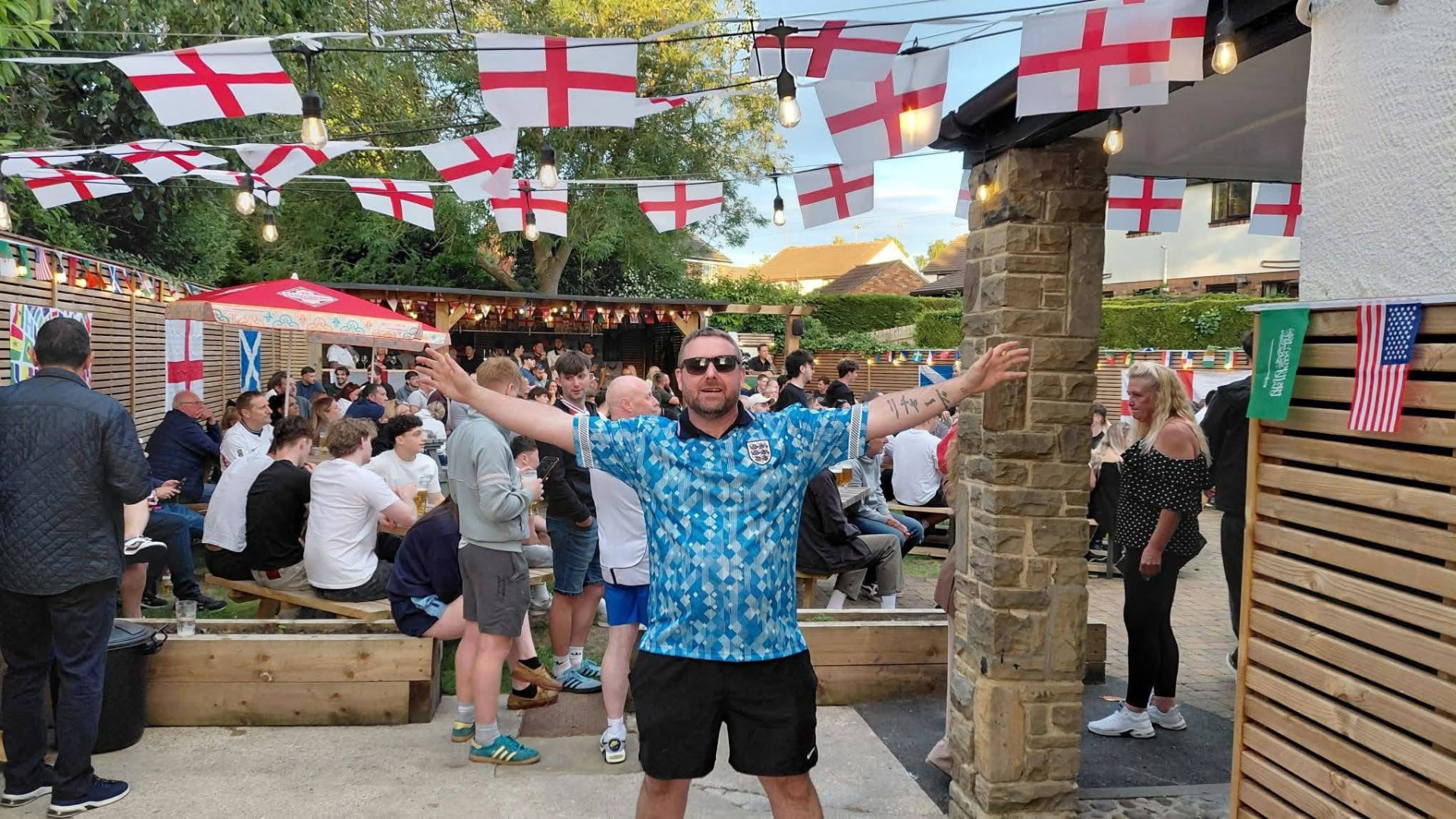 England flags and bunting above busy picnic benches in the beer garden